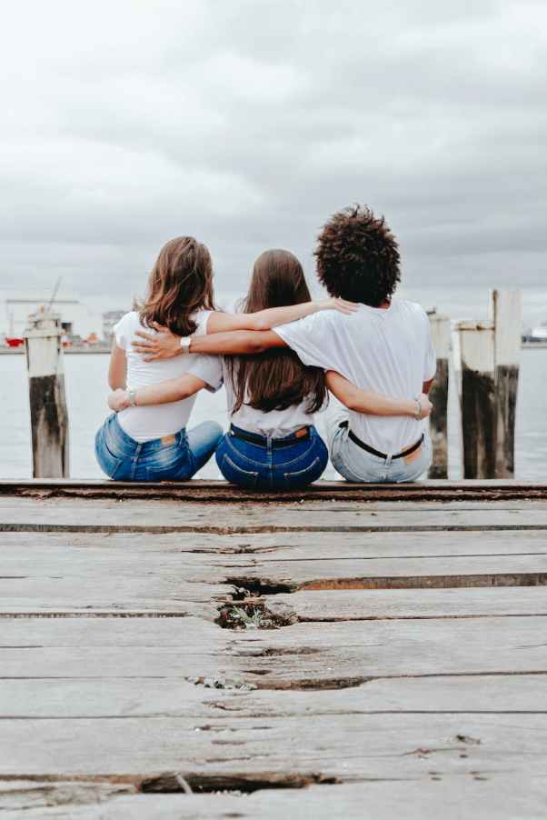 friends sitting on pier hugging