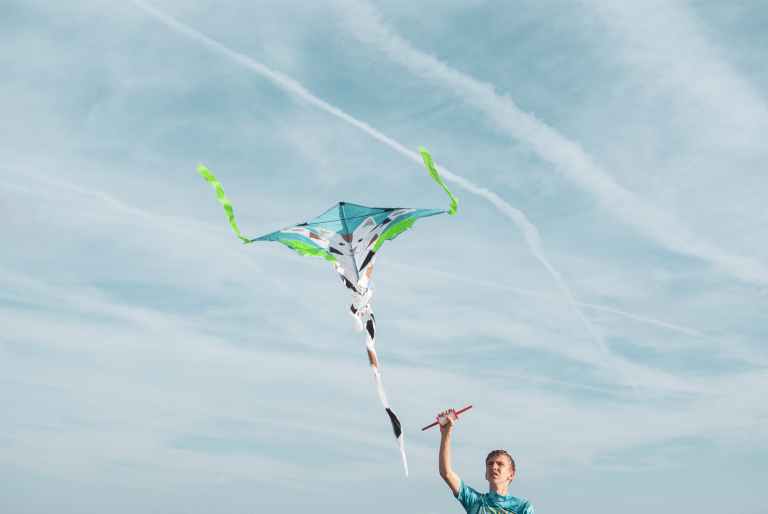 man wearing blue shirt flying kite