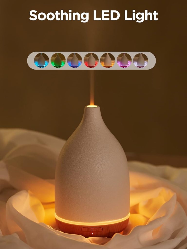 An essential oil diffuser with a soothing LED light, emitting vapor and set against a soft background.