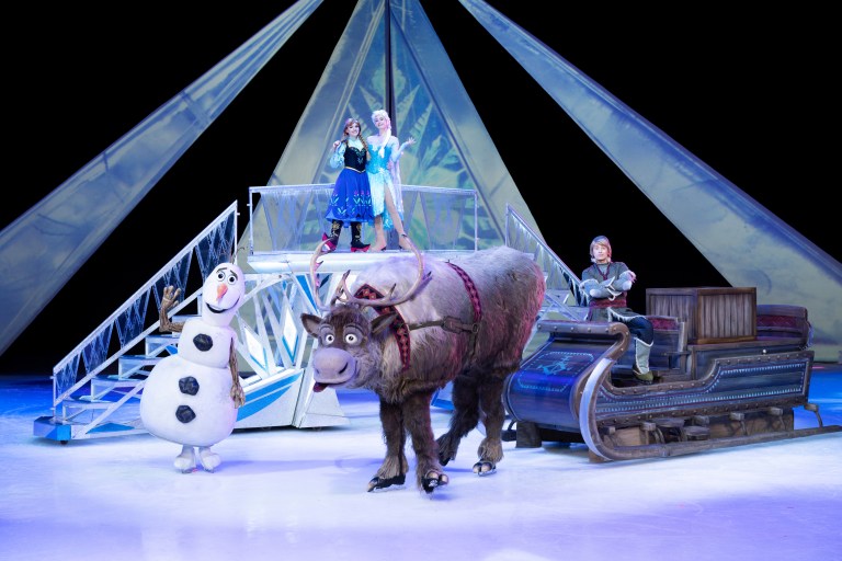 Performance scene from Disney On Ice featuring characters from Frozen, with Anna, Elsa, Olaf, and Sven on stage.