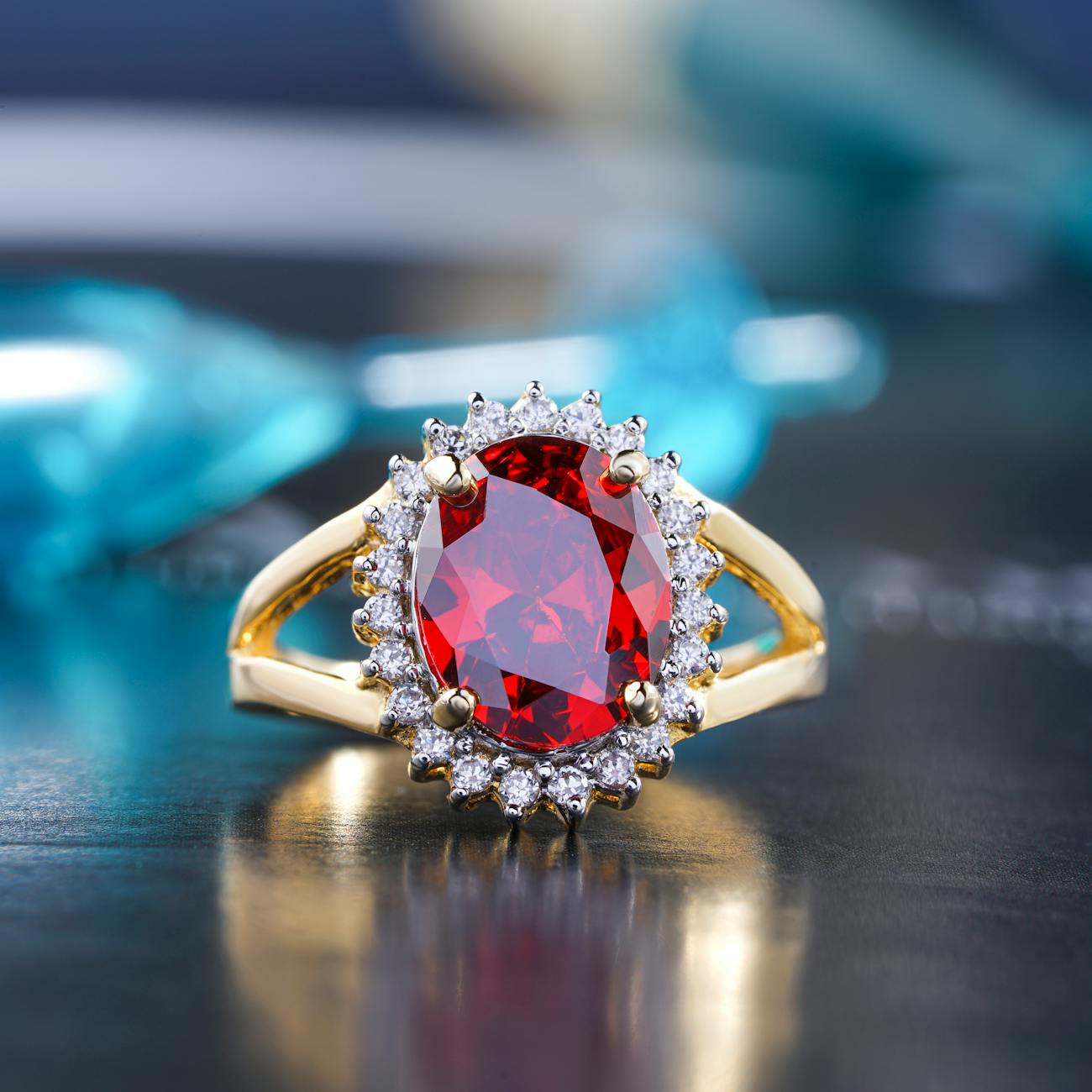 A close-up of a gold ring featuring a large oval red gemstone surrounded by sparkling white diamonds.