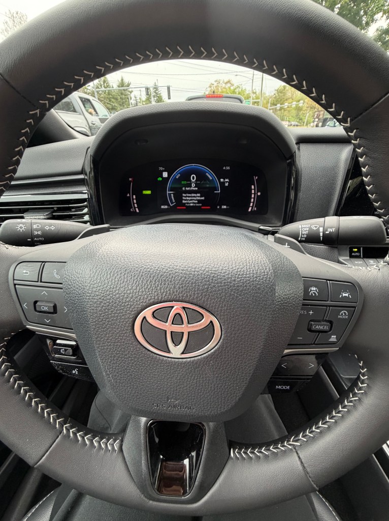 Interior view of a Toyota vehicle focusing on the steering wheel, dashboard, and digital display.