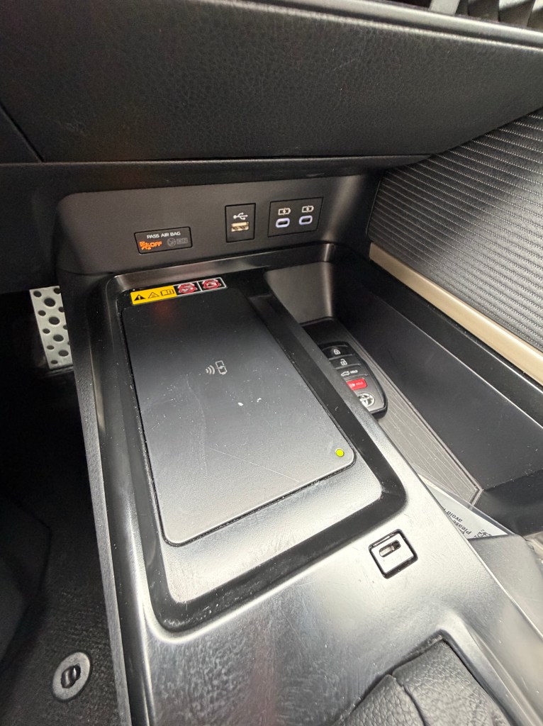 Close-up view of a car's center console showing a wireless charging pad, USB ports, and controls.