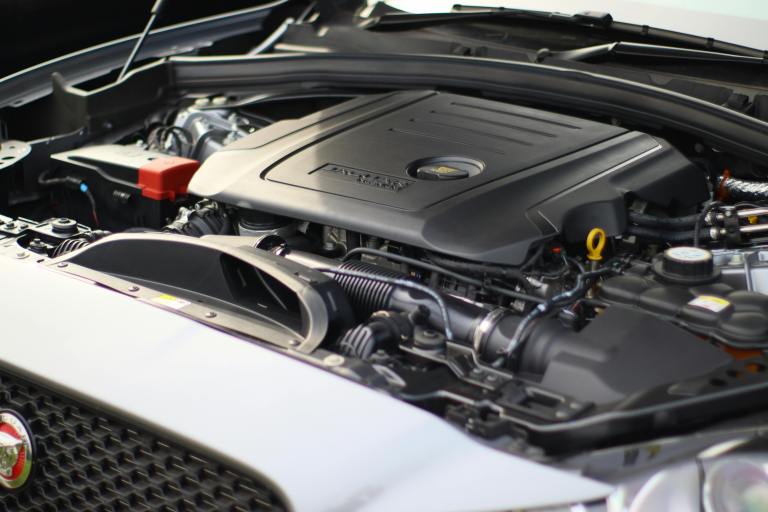 Close-up view of a car engine with a focus on the engine cover and various components visible, highlighting detailed mechanical features.